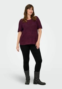 Violeta īsām piedurknēm augšdaļa ir kombinēta ar melnajām legingām un melnajām zābakiem līdz ceļiem ar sprādzēm un akcentiem. Gluda, viegla tekstūra.