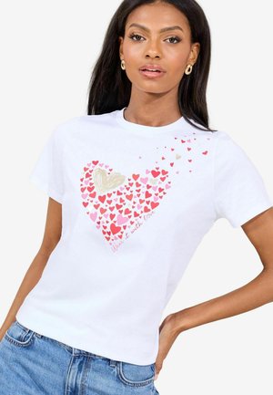 White cotton t-shirt featuring a heart design composed of various pink hearts and a golden heart, with text reading "Wear it with love."