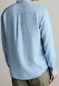 Lichtblauw, langemouwen shirt van gestructureerde stof, met een button-down kraag en detail op de rugpas. Knopen op de manchetten.