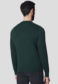 Zielony sweter dzianinowy z okrągłym dekoltem, ściągaczami przy mankietach i dole, charakteryzuje się gładką strukturą bez wzorów i ozdób.