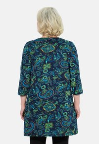 Marineblå kjole med paisley- og blomsterprint i grøn, blå og gul. Har trekvartlange ærmer og lige skæring.