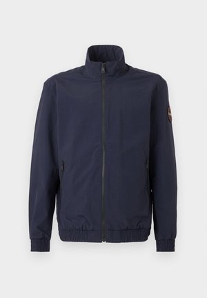 Námornícky modrá vetrovka na zips so stojatým golierom, elastickými manžetami a lemom, bočnými vreckami so zipsom a kruhovou nášivkou so symbolom na ľavom hornom rukáve.