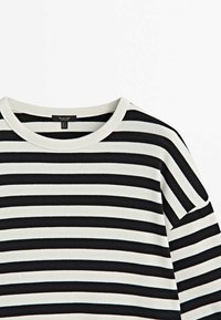 Mustavalkoinen vaakastriipellinen pitkähiha-paita pyöreällä kaula-aukolla ja näkyvällä brändilapulla kauluksessa.