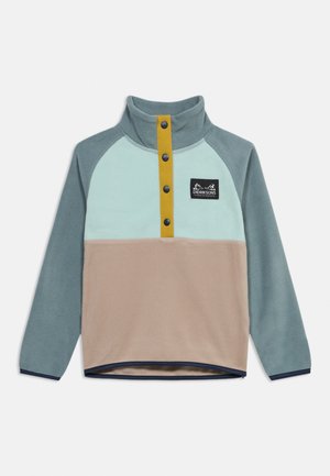 Fleece pullover with light blue upper, beige lower, teal sleeves, yellow button placket, and black logo patch on chest.