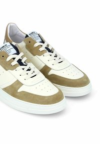 Baskets en cuir blanches et beige avec des accents en daim, bout rond, tige perforée, lacets plats et semelle en caoutchouc texturée.