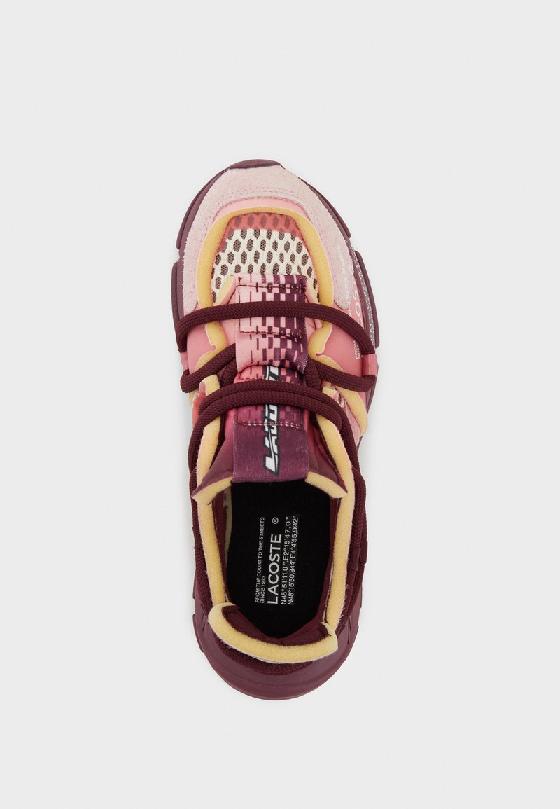 Sneakers Lacoste con una combinazione di colori marrone, rosa e giallo. Parte superiore in rete testurizzata, colletto imbottito e dettaglio del logo sul lato.