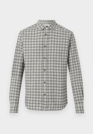 Camicia a maniche lunghe con motivo a quadri bianchi e neri, colletto classico e bottoni marroni su uno sfondo neutro.