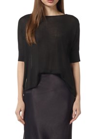Czarny, półprzezroczysty top z dekoltem łódkowym, krótkimi rękawami i asymetrycznym dołem. W zestawieniu z elegancką, ciemną spódnicą.