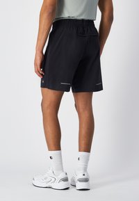 Schwarze Sportshorts aus leichtem Material mit einem elastischen Bund. Verfügt über reflektierende Akzente und eine Gesäßtasche zur Stauraum.