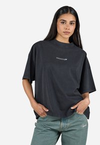 T-shirt noir en coton oversized avec un col montant et des manches courtes. Présente un logo blanc "PEGADOR" sur le devant. Coupe décontractée et ample.