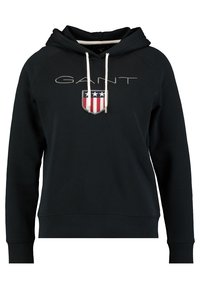 Sudadera con capucha negra y bolsillo frontal, que presenta "GANT" en plata y un logo de escudo con acentos en rojo, blanco y azul.