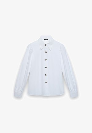 Blusa bianca a maniche lunghe con colletto a punta e sei bottoni decorativi argentati sul davanti, polsini leggermente arricciati.
