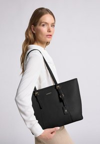 Borsa a tracolla nera in pelle con superficie testurizzata, doppi manici e dettagli in metallo dorato. Logo visibile sul davanti.