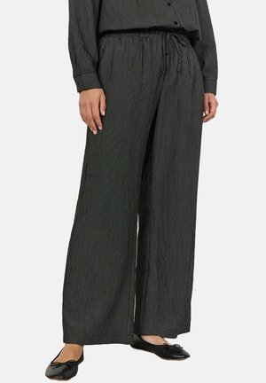 Black wide-leg pants with vertical white stripes, featuring an elastic waistband and drawstring. Tapered hem with a soft, textured finish.