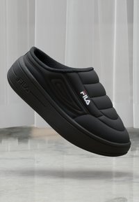 Svart slip-on sko med polstret overdeler, teksturert design og gummisåle. Har FILA-logo i rødt på siden. Myk innvendig fôr.