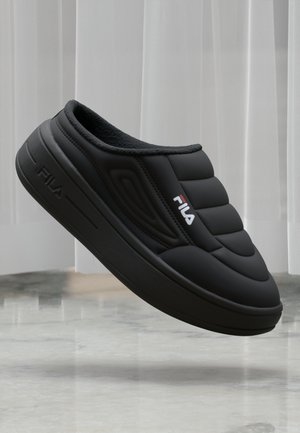 Svart slip-on sko med polstret overdeler, teksturert design og gummisåle. Har FILA-logo i rødt på siden. Myk innvendig fôr.