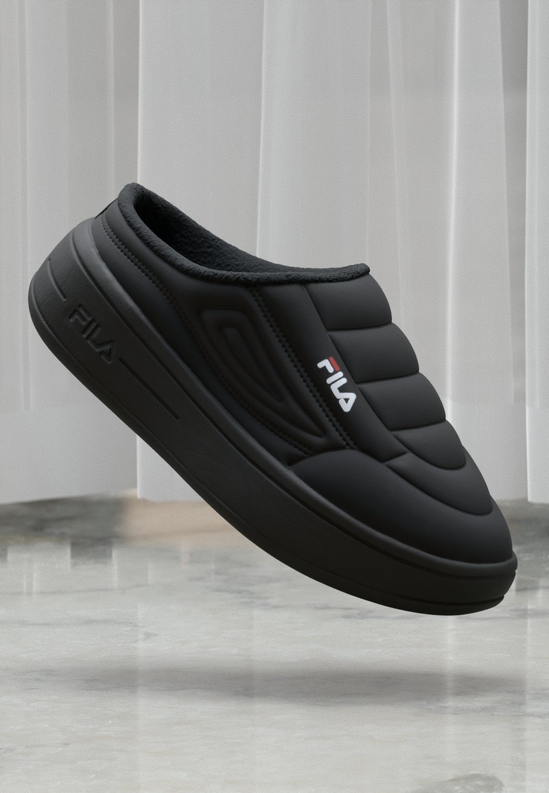 Svart slip-on sko med polstret overdeler, teksturert design og gummisåle. Har FILA-logo i rødt på siden. Myk innvendig fôr.