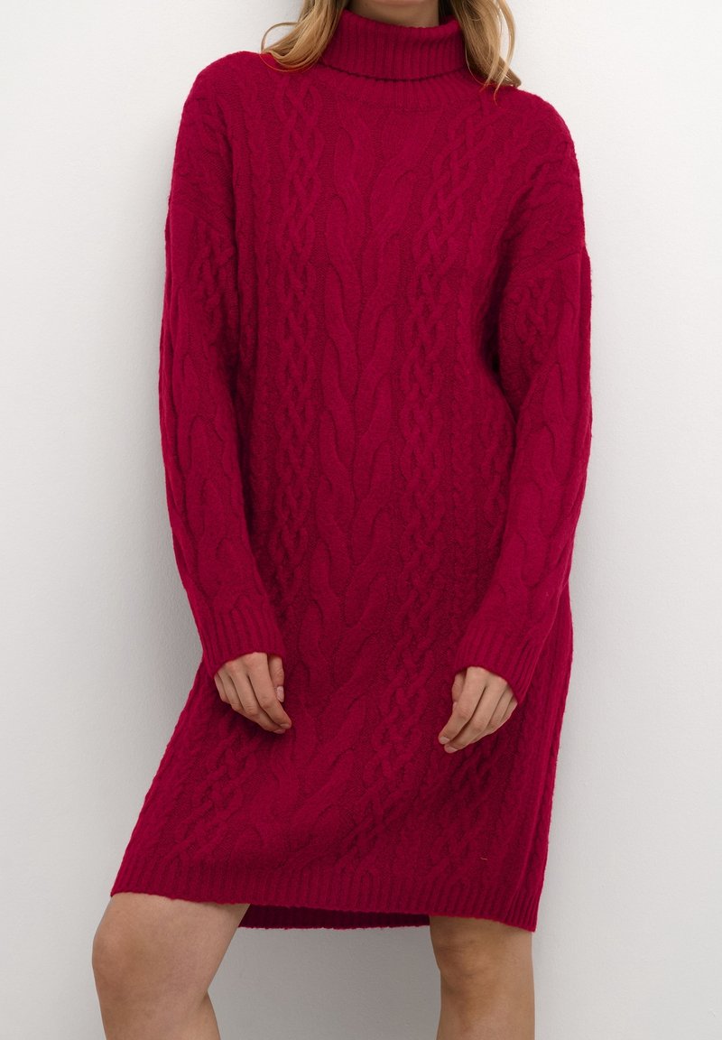 Strikket sweaterkjole i fuchsia med høj hals. Har kabelstrik tekstur, lange ærmer og en afslappet pasform.