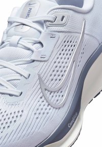 Scarpa da corsa Nike azzurro chiaro con upper in mesh testurizzato, sistema di allacciatura integrato, dettagli metallici argentati e suola ammortizzata.