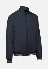 Chaqueta bomber de color azul marino con cierre frontal, cuello alzado y puños y dobladillo acanalados a rayas en acentos rojos y blancos. Tela suave y ligera.