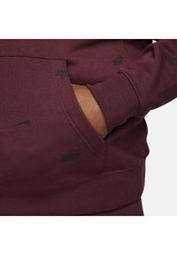 Maroon hoodie featuring small black Nike logos, a front pocket, ribbed cuffs, and a smooth texture. The design is simple and modern.