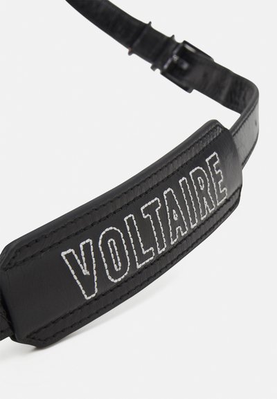 Bracelet en cuir noir avec "VOLTAIRE" embossé en couture blanche. Caractéristiques : texture lisse et attache de boucle réglable.