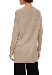 Beige gebreid sweater met een geribde zoom en manchetten, met een relaxte pasvorm en lange mouwen, benadrukt een gestructureerd materiaal en een eenvoudig ontwerp.