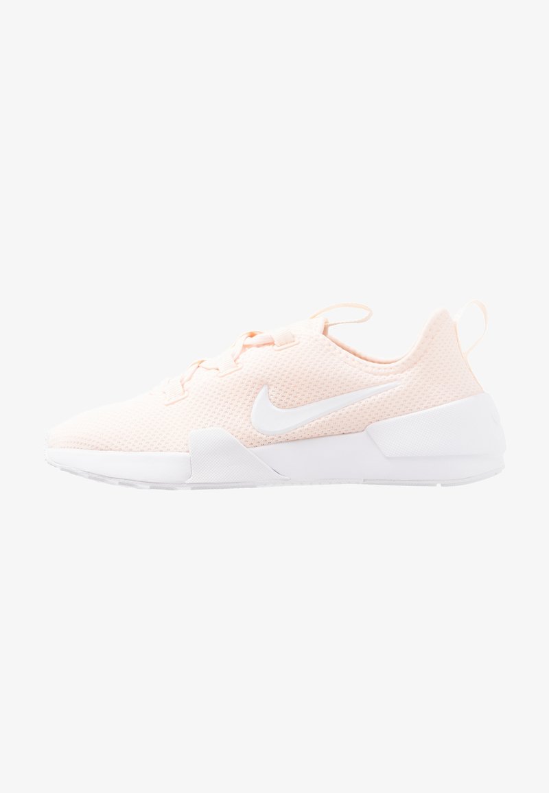 Baskets de sport rose clair avec semelle blanche, dessus en mesh, lacets et logo Nike swoosh blanc sur le côté, vue de la gauche.