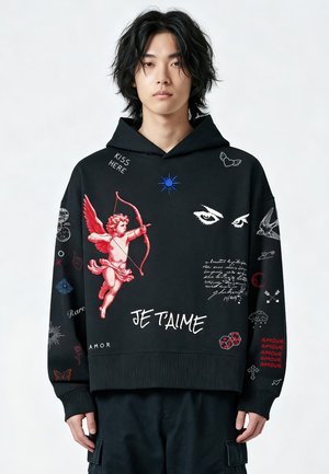 Jonge man draagt een zwarte hoodie met rode cupido, witte ogen, zinnen zoals "JE T'AIME," "KISS HERE" en andere kleine grafische symbolen.