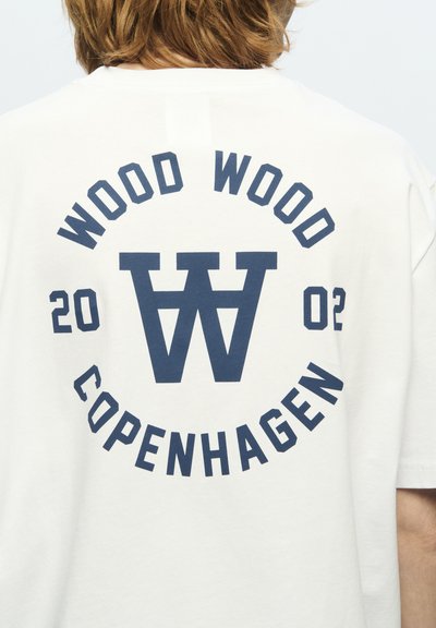 T-shirt in cotone bianco con una grande grafica blu navy sul retro, con il testo "WOOD WOOD" e "COPENHAGEN", disposto in un layout circolare e la data "2002."