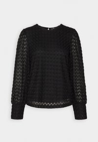 Blouse noire texturée avec de longues manches transparentes et un col rond. Présente un motif hexagonal et un ourlet délicat. Fermeture par bouton au dos.