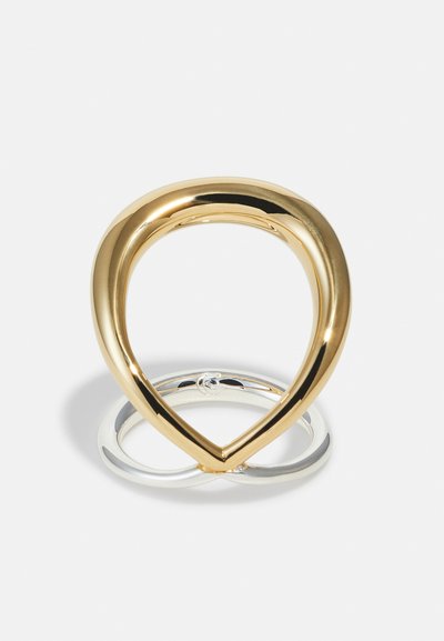 Zwei verbundene Ringe mit einem goldenen, tropfenförmigen Ring, der mit einem kleineren silbernen, runden Ring auf weißem Hintergrund verbunden ist.