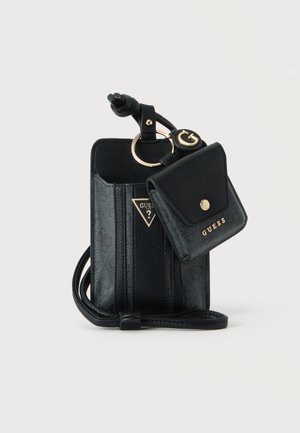 Μαύρο Guess crossbody θήκη κινητού με προσαρτημένη μικρή θήκη για κέρματα και εξαρτήματα σε χρυσό χρώμα σε λευκό φόντο.