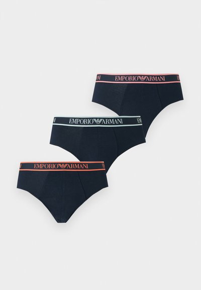 Τρία σκούρα μπλε εσώρουχα με ελαστικές ζώνες στη μέση σε ροζ, ανοιχτό μπλε και πορτοκαλί, το καθένα με την επωνυμία "EMPORIO ARMANI" και λογότυπο.
