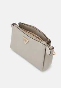 Beige syntetisk håndtaske med et struktureret design, der har et guld-tone logo, top lynlås og et indre rum. Tekstureret overflade.