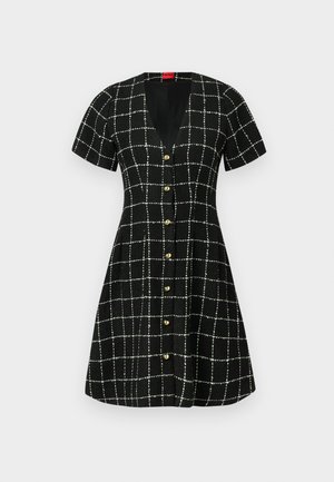 Čierne šaty s krátkymi rukávmi, výstrihom do V a prednými gombíkmi. Majú bielu mriežkovú vzorku a rozšírenú sukňu. Štruktúrovaná tkanina.