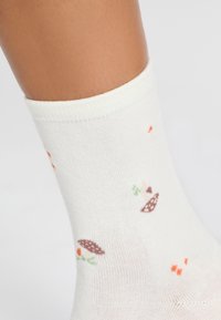 Calze fino al ginocchio di colore bianco sporco con motivi di ricci marroni, fiori arancioni e accenti verdi, realizzate in tessuto morbido ed elastico.