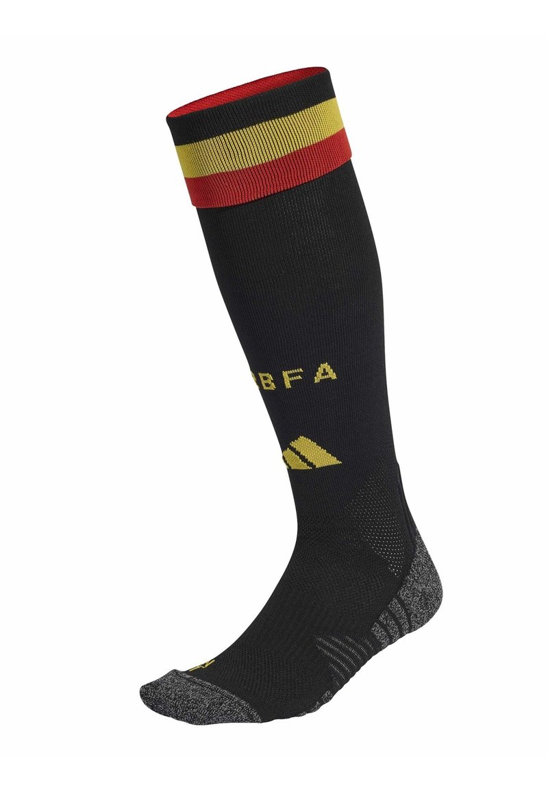 Calcetín negro hasta la rodilla con puño a rayas en rojo, amarillo y negro. Presenta un logo y texto amarillos. Suela texturizada en gris. Diseño deportivo.