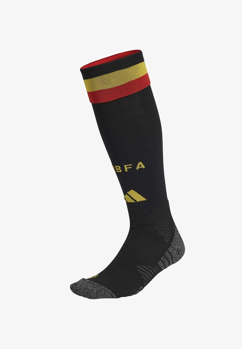 Calcetín negro hasta la rodilla con puño a rayas en rojo, amarillo y negro. Presenta un logo y texto amarillos. Suela texturizada en gris. Diseño deportivo.