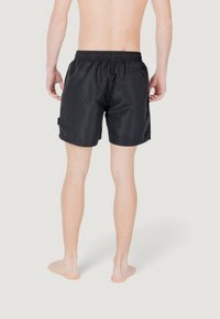 Bañador negro con cinturilla elástica, un bolsillo trasero y una tela suave y liviana, diseño hasta la rodilla.