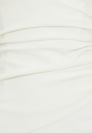 Valkoinen teksturoitu kangas, jossa on useita ripustettuja poimuja, hienovarainen kiilto ja pehmeä pinta, joka sopii erinomaisesti vaatteisiin tai verhoilukäyttöön.