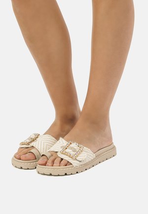 Sandalias de playa ligeras en color beige claro, con una parte superior de tejido texturizado y un gran hebilla decorativa adornada con strass. Suela de goma con tracción.