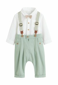 Camicia bianca a maniche lunghe per bambino con papillon beige abbinata a pantaloni verde chiaro con bretelle e dettagli in bottoni.