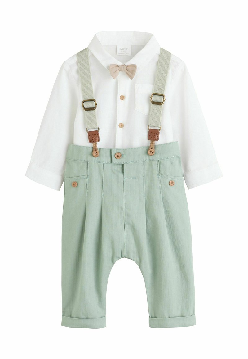Camicia bianca a maniche lunghe per bambino con papillon beige abbinata a pantaloni verde chiaro con bretelle e dettagli in bottoni.