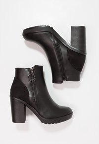 Stivali ankle neri in pelle liscia e suede, con tacco a blocco alto, zip laterale e suola texturizzata per una migliore aderenza.
