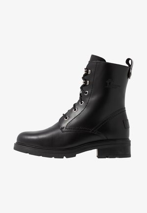 Bota de piel negra hasta el tobillo con punta redonda, cordones en la parte delantera, acentos de ojales y una suela de goma texturizada. Cuenta con una lengüeta en el talón.