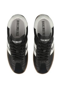 Černobílé tenisky s gumovou podrážkou, se hladkým koženým svrškem, kulatou špičkou a kontrastními logovými akcenty na boku.