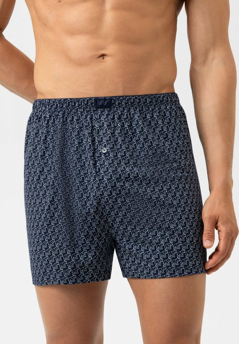Marineblaue Baumwollboxershorts mit einem sich wiederholenden weißen Tiermuster. Elastischer Bund mit Verschluss vorne mittels Knopf.