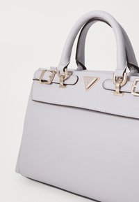 Borsa a tracolla in pelle grigia con hardware dorato e doppie fibbie decorative. Presenta una forma strutturata e un logo impresso sulla parte anteriore.