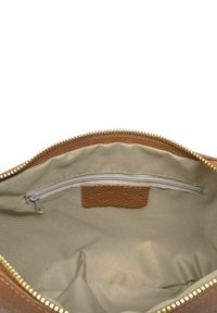 Wnętrze brązowej torby skórzanej z gładkim, beżowym podszewkiem. Posiada kieszeń na zamek oraz skórzaną metkę o fakturowanej powierzchni. Złote wykończenie zamka.